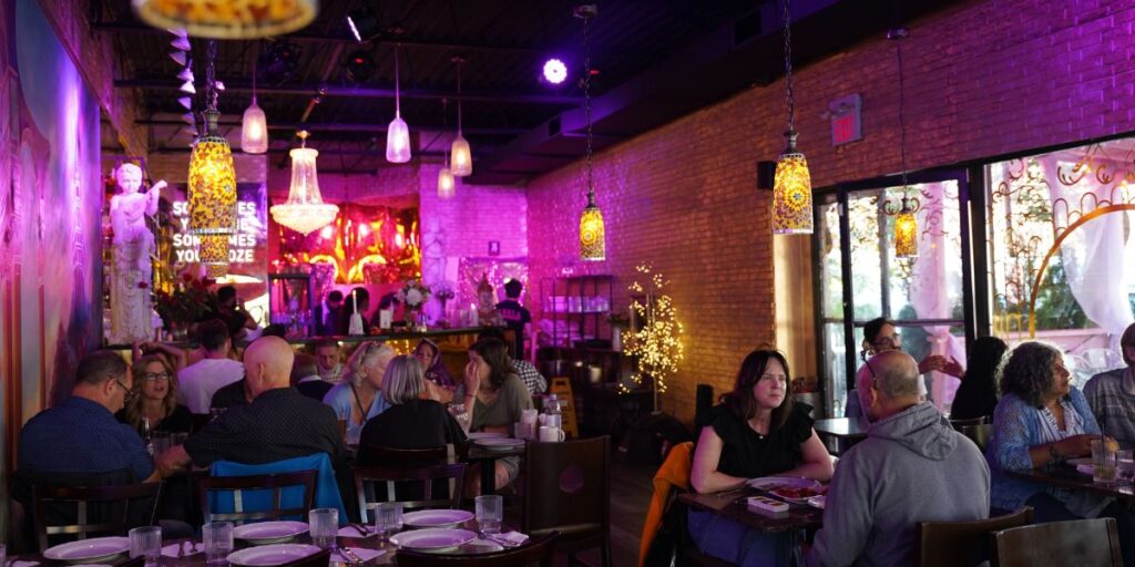 A group of people dining at a restaurant with purple ambient lighting.