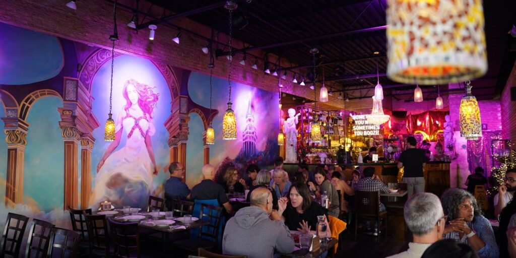 A restaurant with people sitting at tables and hanging lights.