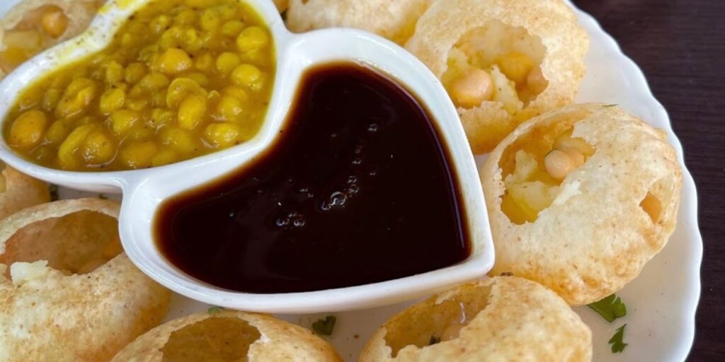 A plate of Pani Puri, crispy puris filled with spicy water, potatoes, and chickpeas, a popular street food in India.