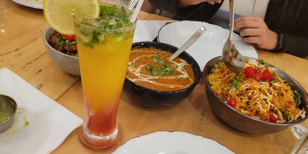 A table at Leela Indian Food Bar in Dundas, featuring a variety of food and drinks, creating a symphony of flavors & textures.