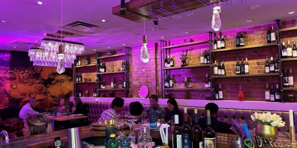 A restaurant with purple lighting and wine bottles on display.