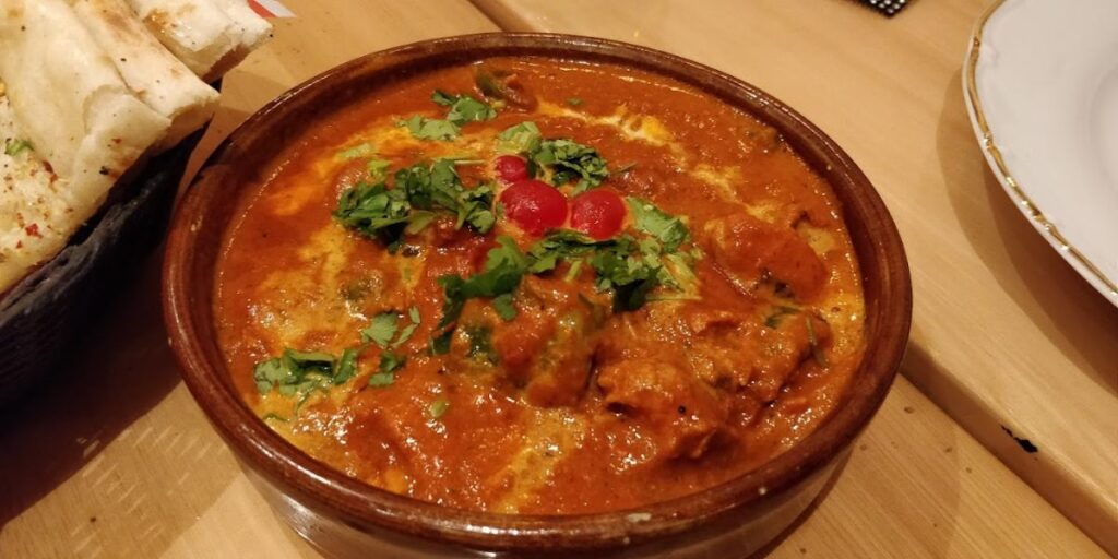 A bowl of curry and bread on a table.