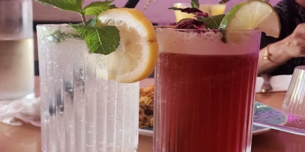 Two white wine spritzers with ice and mint leaves on a wooden table. Refreshing and elegant cocktails perfect for any occasion.