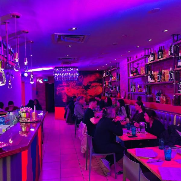 A view of Leela Indian Food Bar's interior, illuminated by purple lighting, inviting guests to enjoy a memorable dining experience.