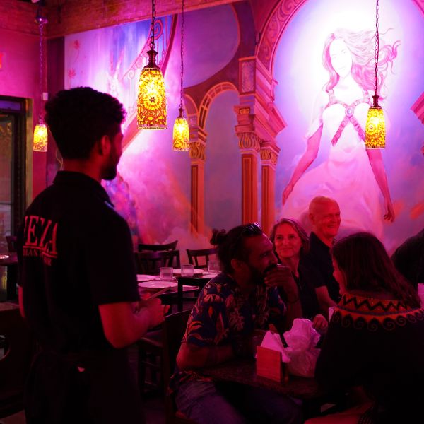 A man engages with diners at Leela Indian Food Bar, where attentive staff enhance the dining experience with personalized service.