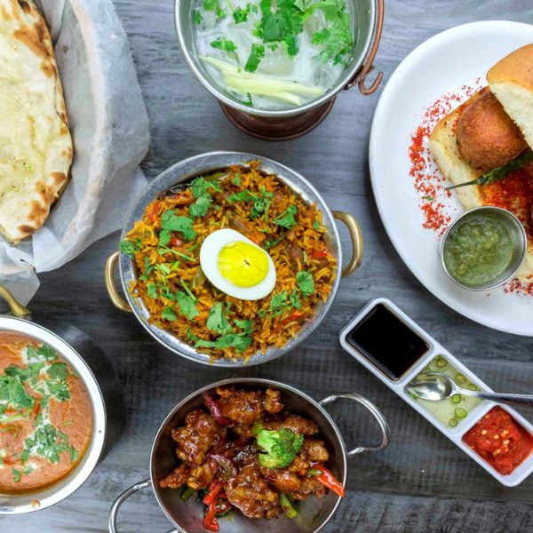 A table displays an array of Indian dishes, including butter chicken, lamb vindaloo, and aromatic biryanis, showcasing culinary diversity.