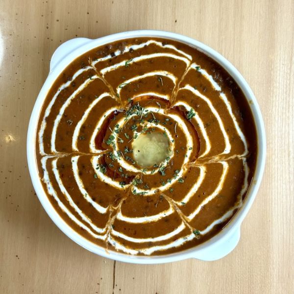 A bowl of soup featuring a decorative spiral design on the surface, showcasing culinary artistry and presentation.