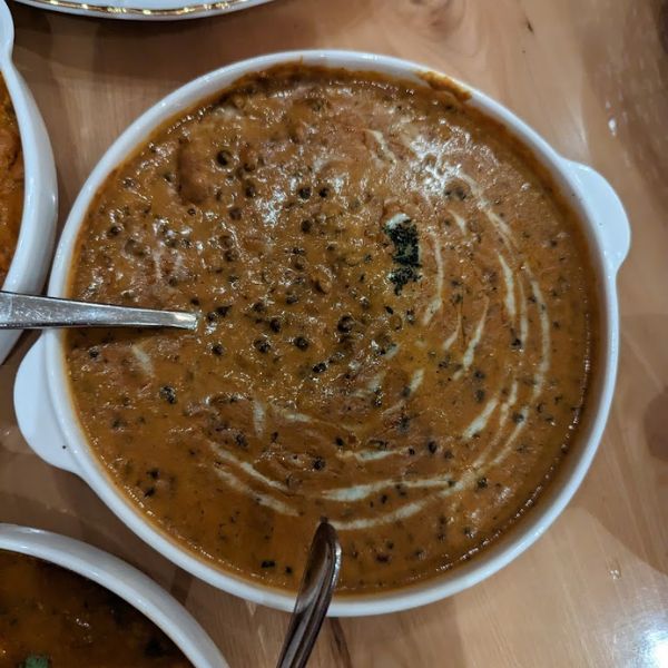 A bowl of rich Dal Makhani soup with a spoon, showcasing high-quality lentils, beans, and fresh cream.