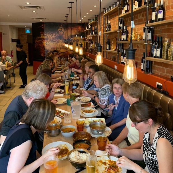  A diverse group of diners enjoying a meal together at a restaurant table, showcasing the vibrant atmosphere of shared dining.